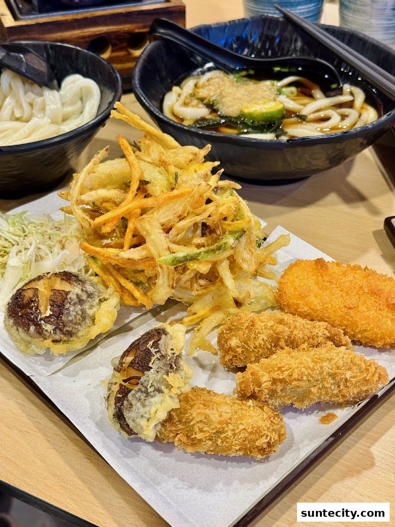 A platter of assorted tempura and two bowls of udon noodles are displayed on a table.