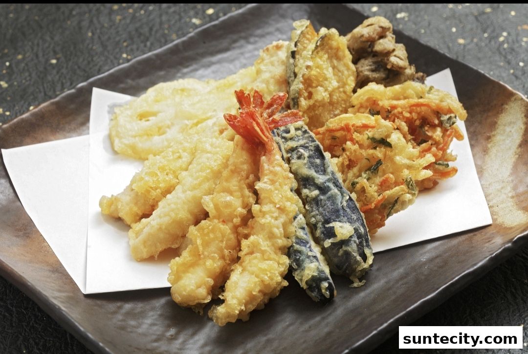 A plate of assorted tempura, including shrimp, eggplant, and vegetables, served on a dark plate.