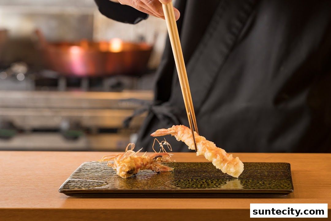 A chef uses chopsticks to place a piece of tempura shrimp onto a rectangular plate.