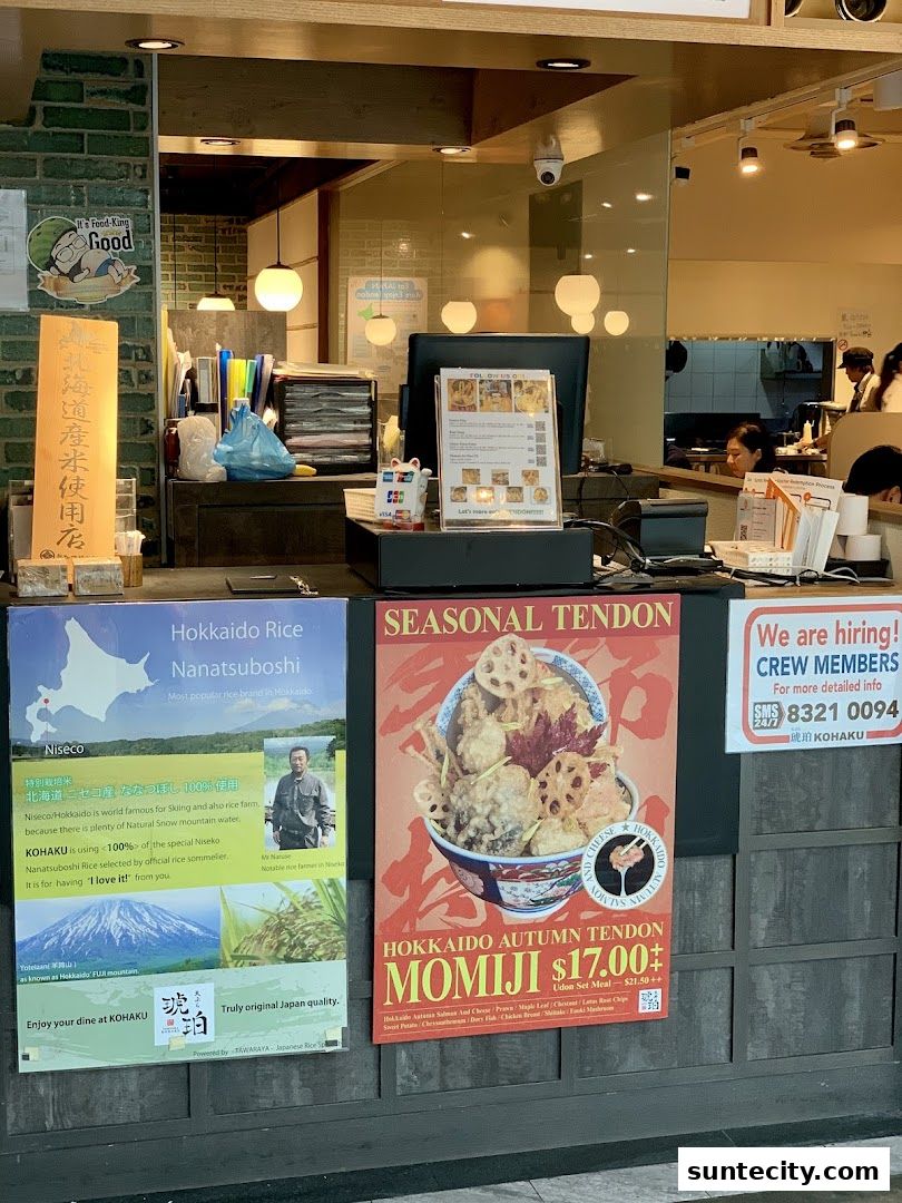 A shop counter with promotional posters for Hokkaido rice and seasonal tendon.