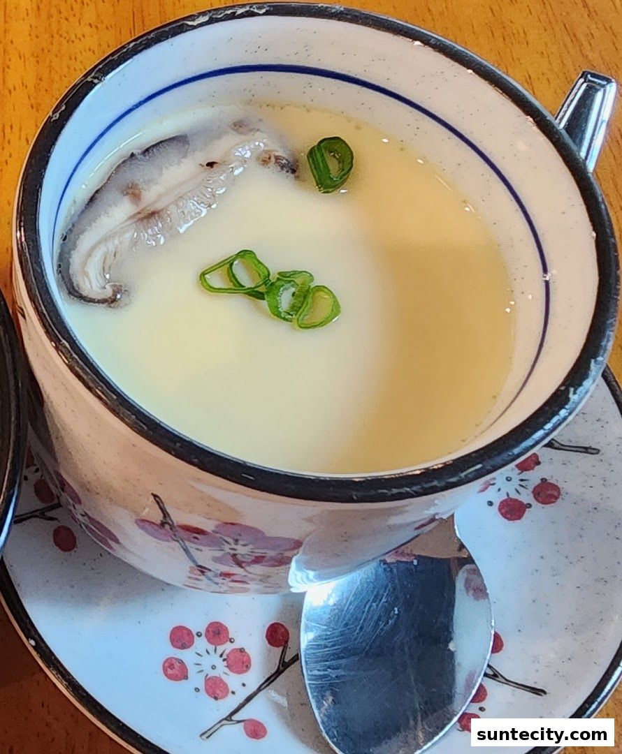 A close-up of a steaming bowl of chawanmushi with shiitake mushroom and scallions.