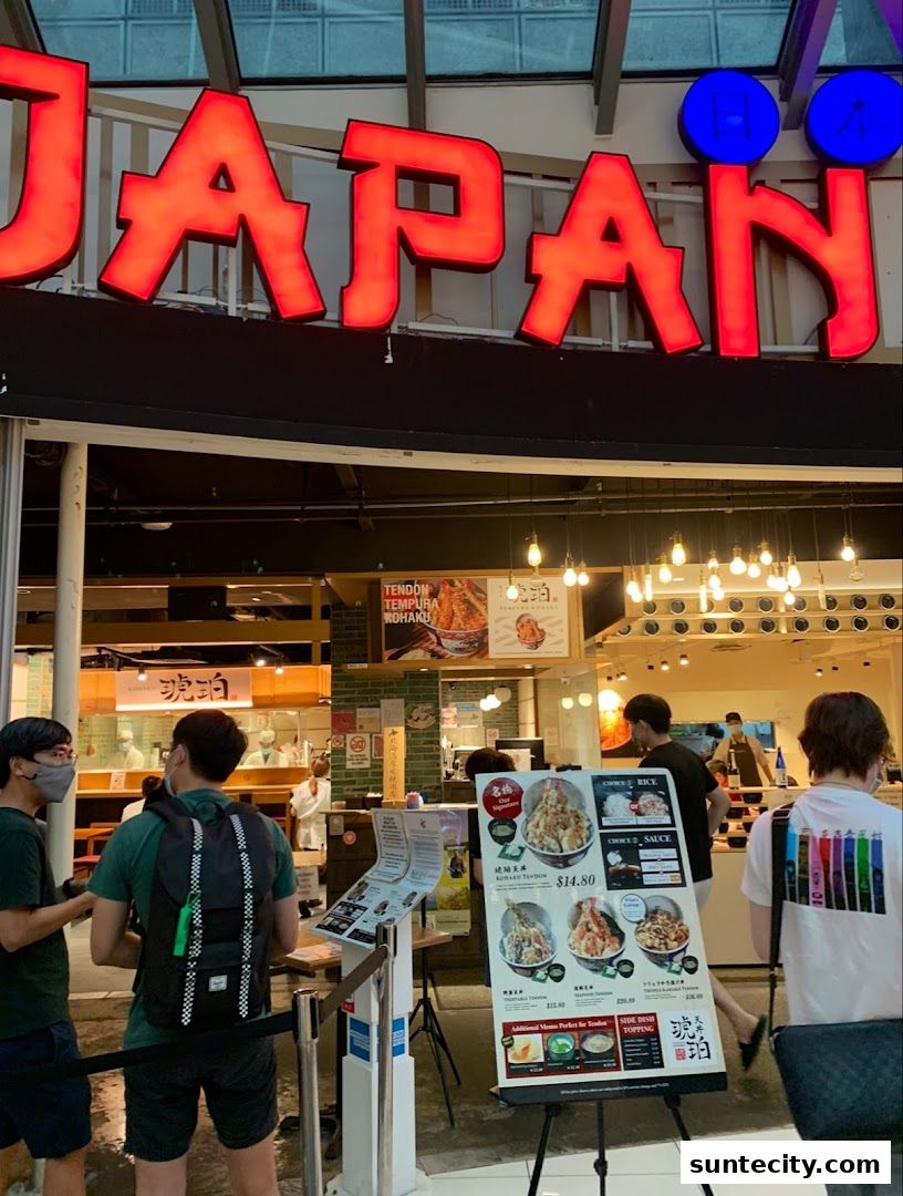 People queuing outside Tendon Kohaku, a Japanese restaurant with a prominent red sign.