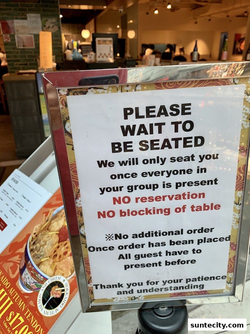 A sign indicating 'Please Wait to Be Seated' with a menu visible on the left.