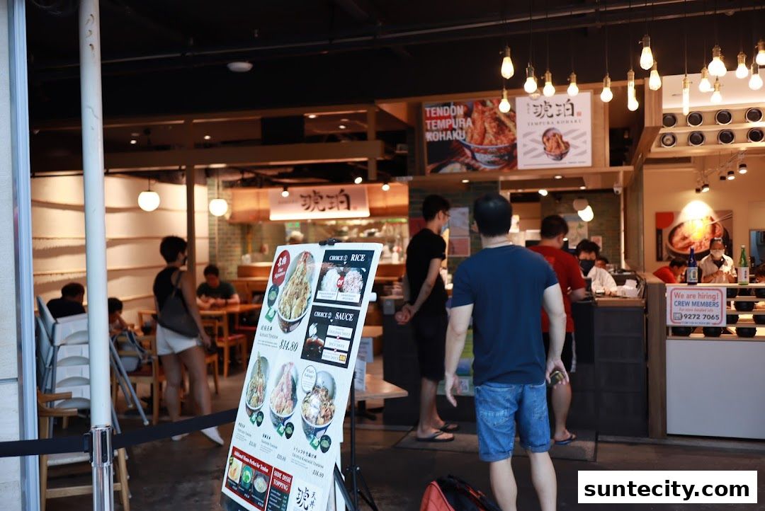 A restaurant storefront with a menu board displaying food items and people queuing.