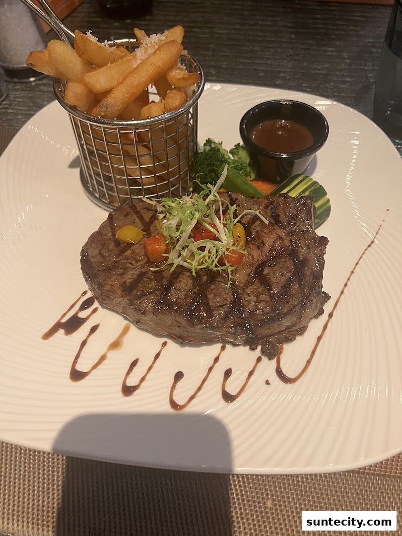 A grilled steak with fries and vegetables served on a white plate.