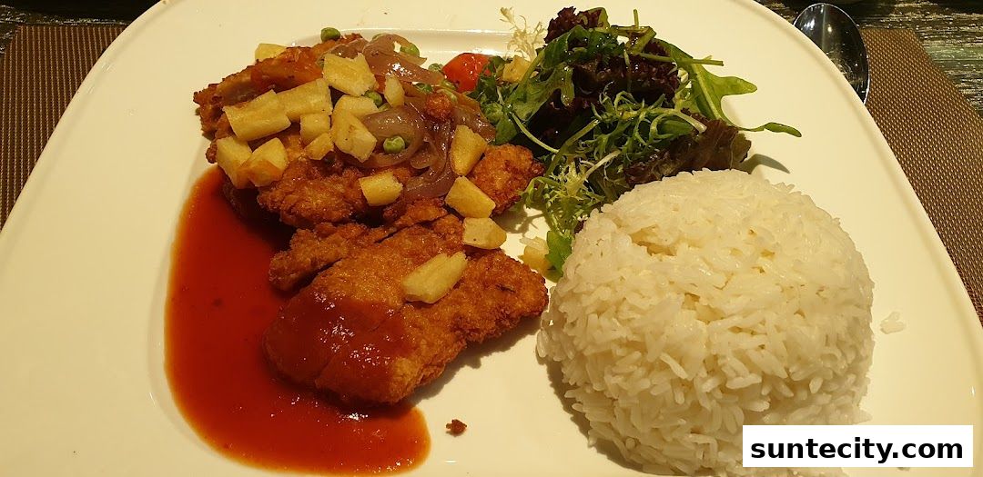 A plate of crispy fried chicken with rice, salad, and sauce.