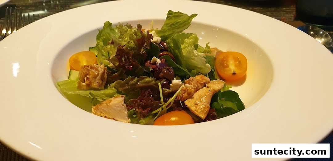 A close-up of a gourmet salad with grilled chicken, cherry tomatoes, and feta cheese.