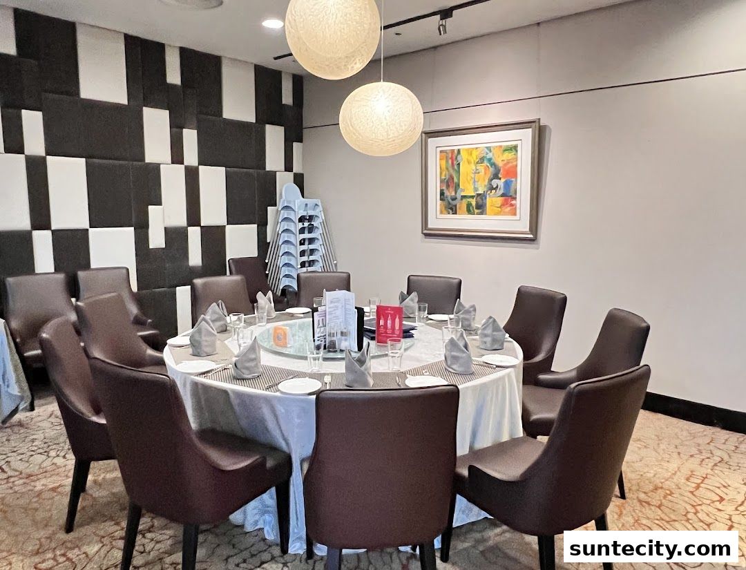 A round dining table set for a group with chairs, napkins, and a painting on the wall.