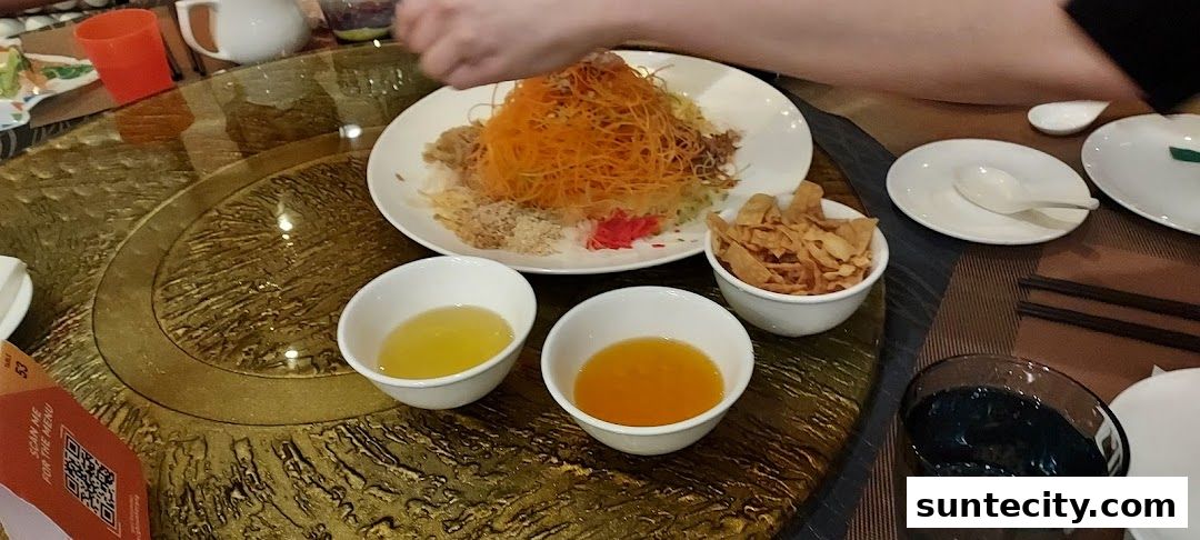 A table setting with a dish of shredded vegetables, sauces, and crispy wonton strips.