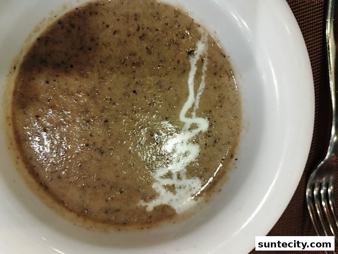 A close-up of a bowl of creamy mushroom soup with a swirl of cream.