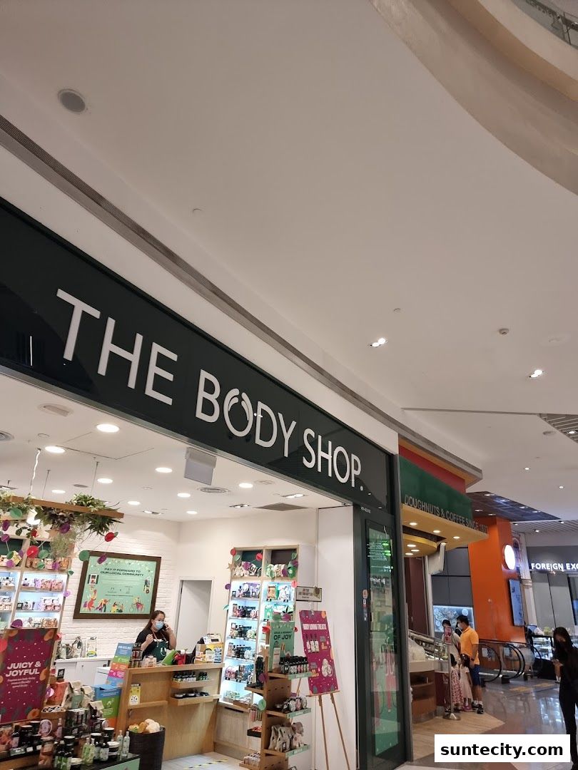 The Body Shop storefront with products displayed inside and a staff member at the counter.