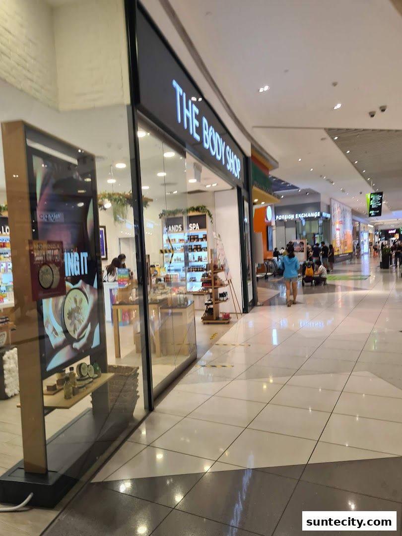 The Body Shop storefront in a brightly lit shopping mall with customers walking by.