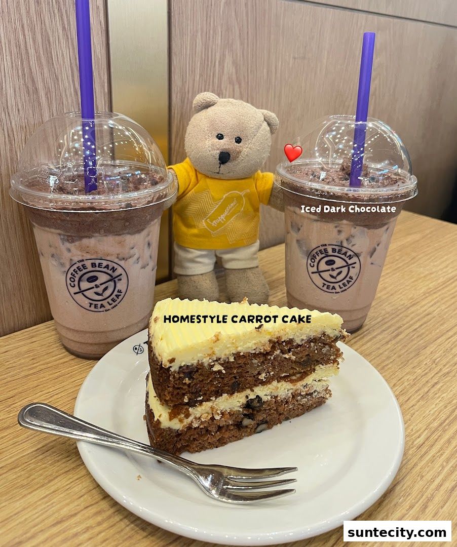 A slice of carrot cake and two iced drinks with a teddy bear.