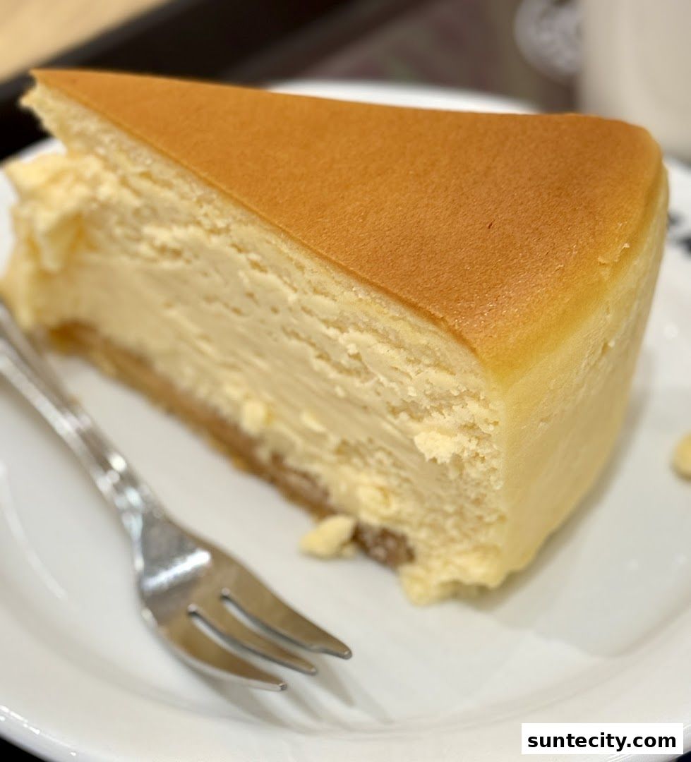 A slice of creamy cheesecake with a fork on a white plate.