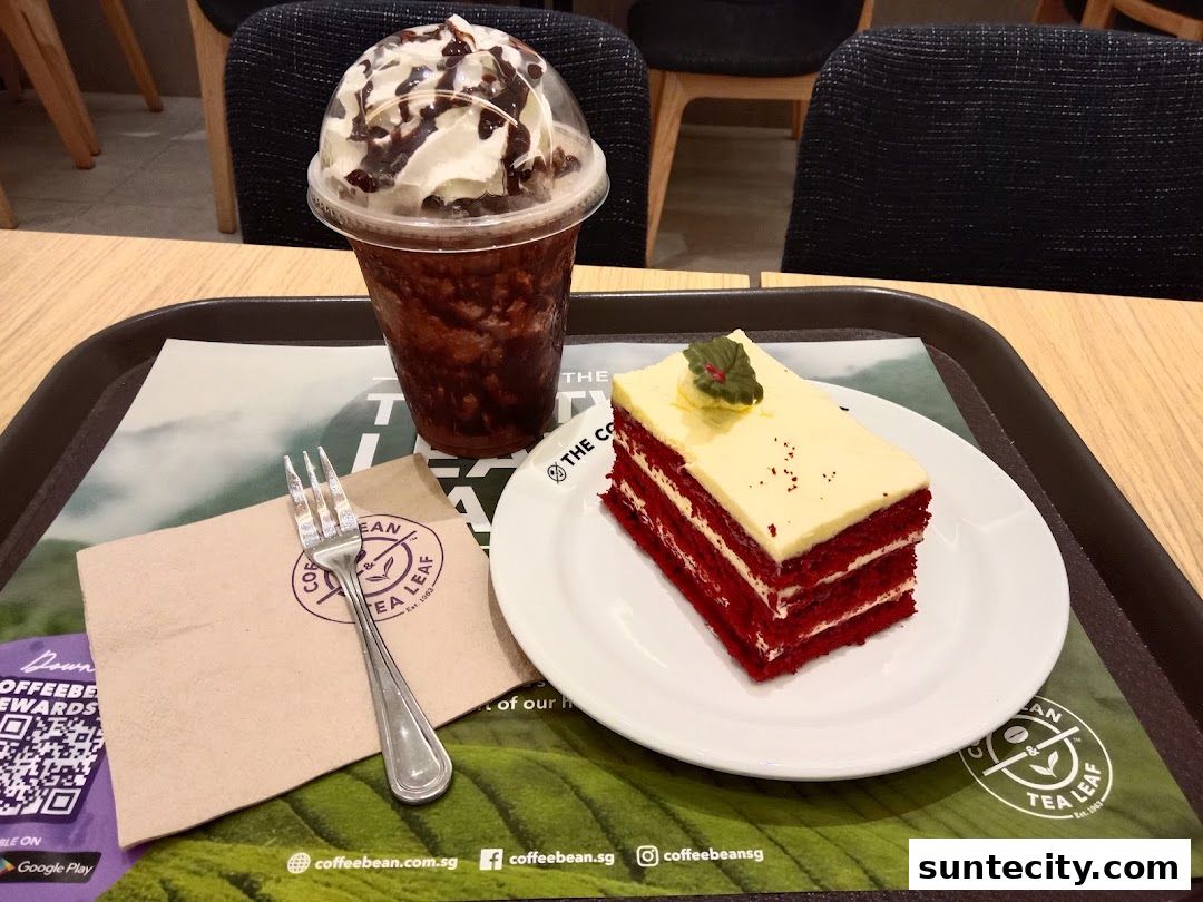 A slice of red velvet cake and a chocolate frappe with whipped cream and chocolate drizzle.