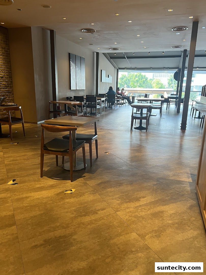 Interior view of a coffee shop with tables and chairs, and people seated.