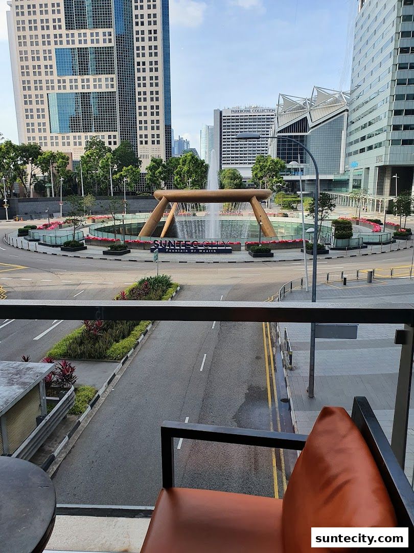 View of Suntec City Fountain of Wealth with surrounding buildings and a chair in the foreground.