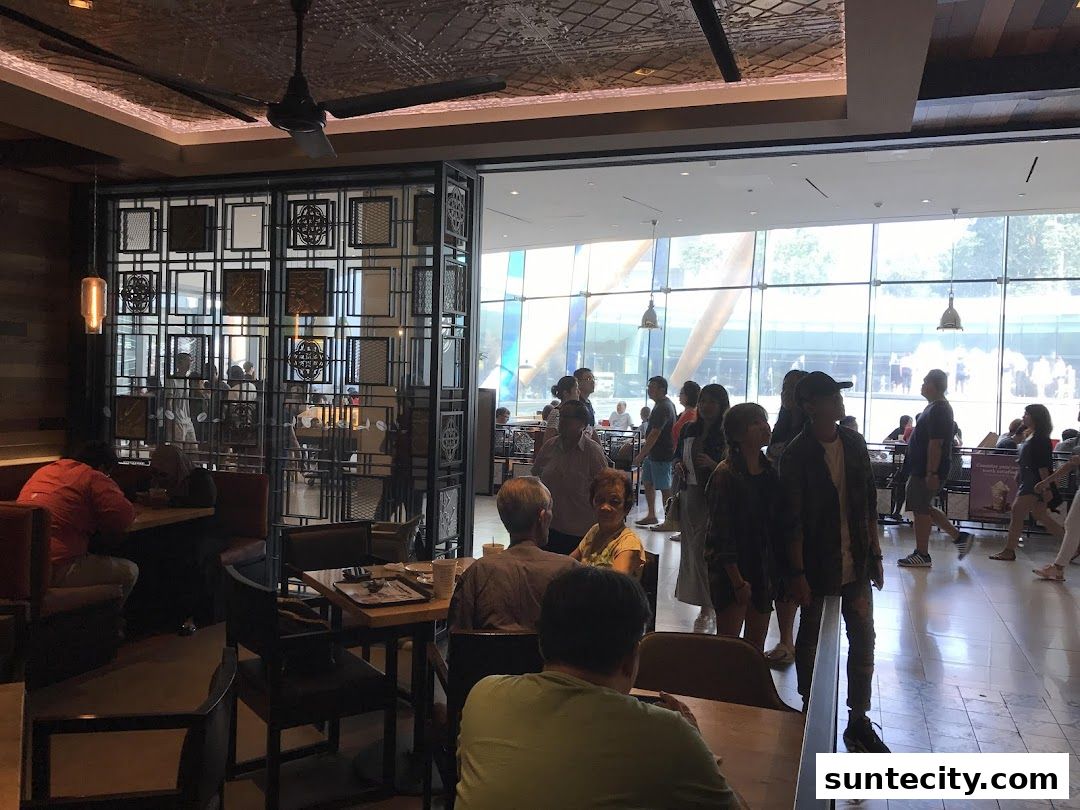 Interior view of The Coffee Bean & Tea Leaf with customers dining and standing near a large window.