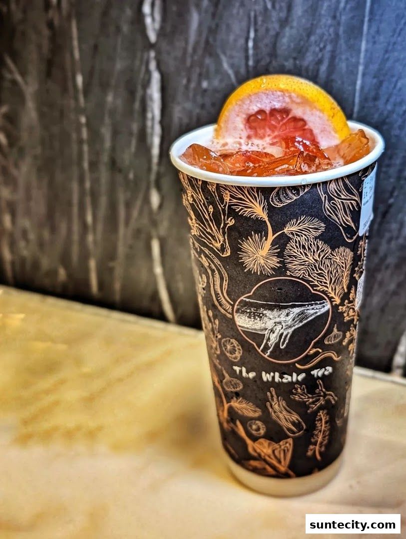 A refreshing drink with grapefruit and ice in a branded cup.