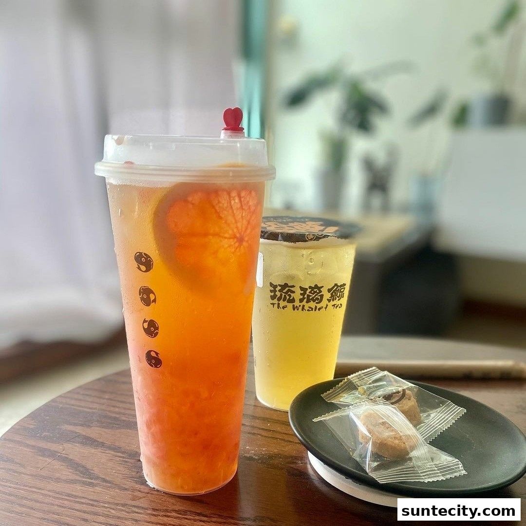 Two refreshing fruit teas and two small cookies on a wooden table.