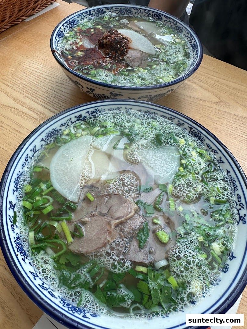 Two steaming bowls of Lanzhou beef noodles with fresh ingredients.