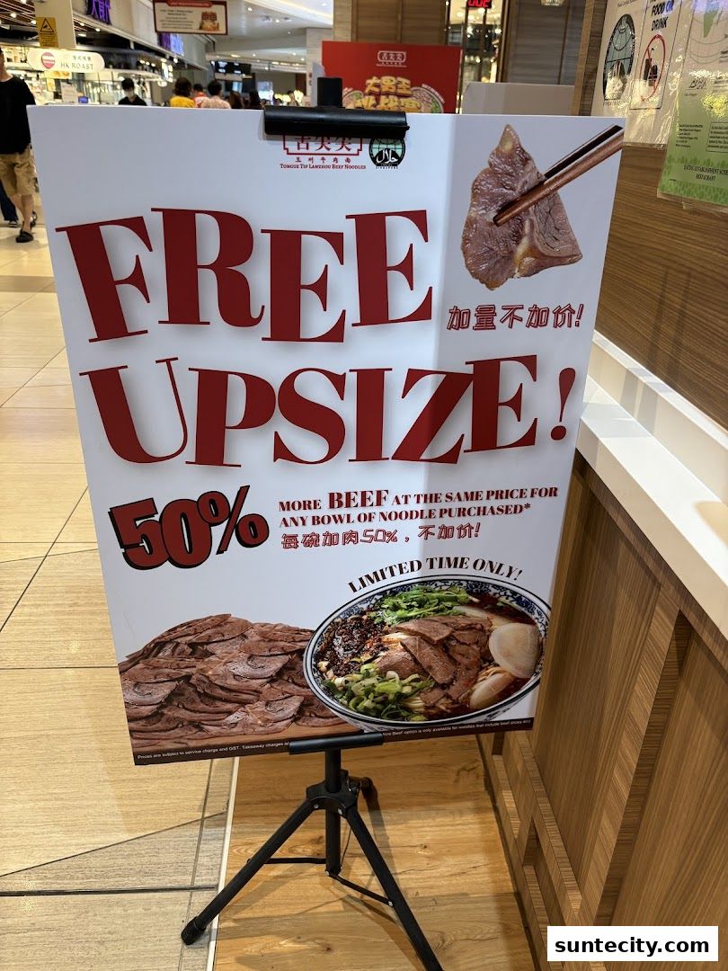 A promotional sign for Tongue Tip Lanzhou Beef Noodles offering a free upsize with more beef.