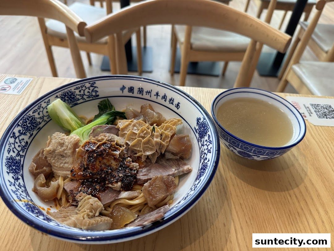 A bowl of Lanzhou beef noodles with tripe and a side of broth.