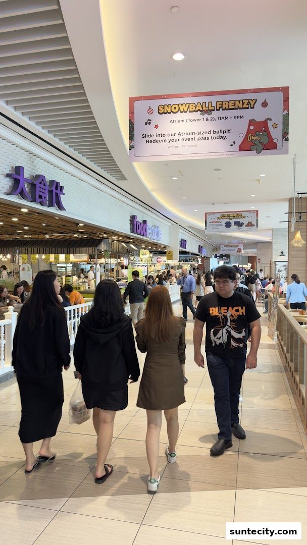 People walking in a mall corridor with shops and a promotional banner overhead.