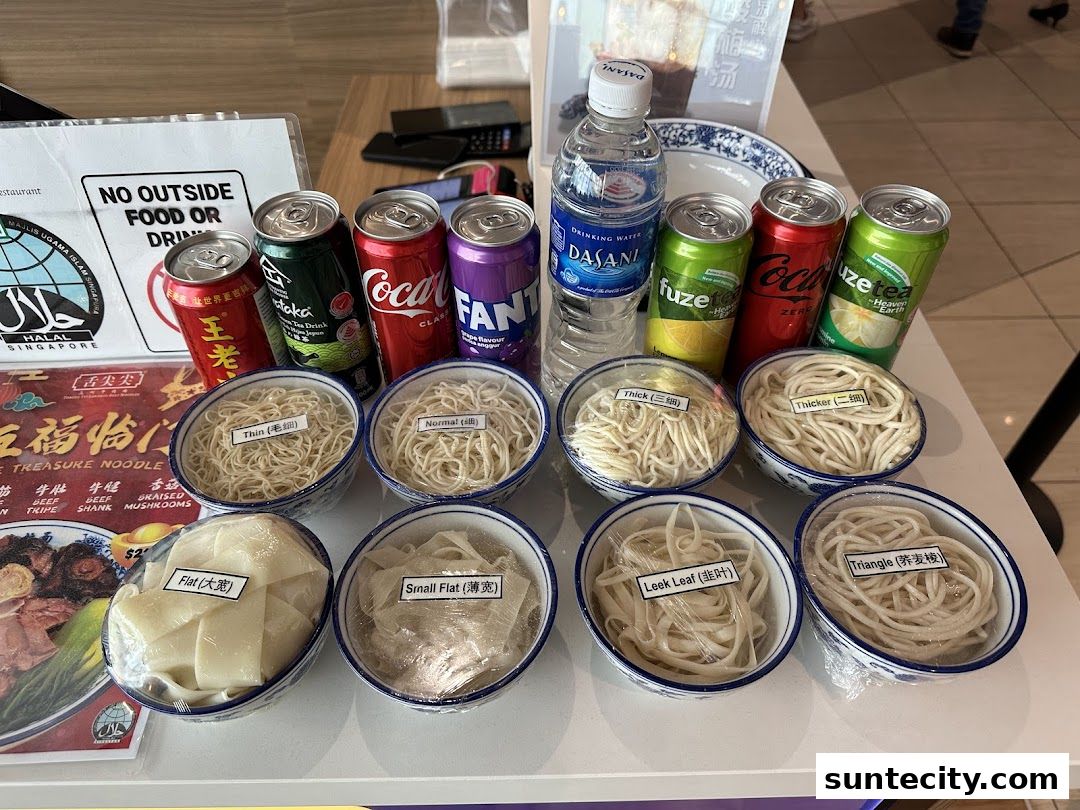 A selection of different noodle types and canned drinks are displayed on a table.