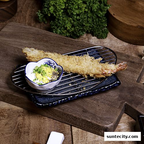 A crispy fried shrimp served with a dipping sauce on a wooden board.
