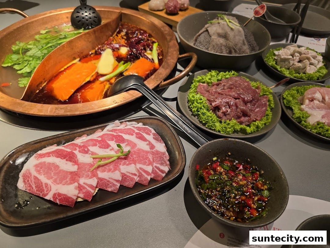 A table laden with various ingredients for hotpot, including thinly sliced meats and a bubbling broth.