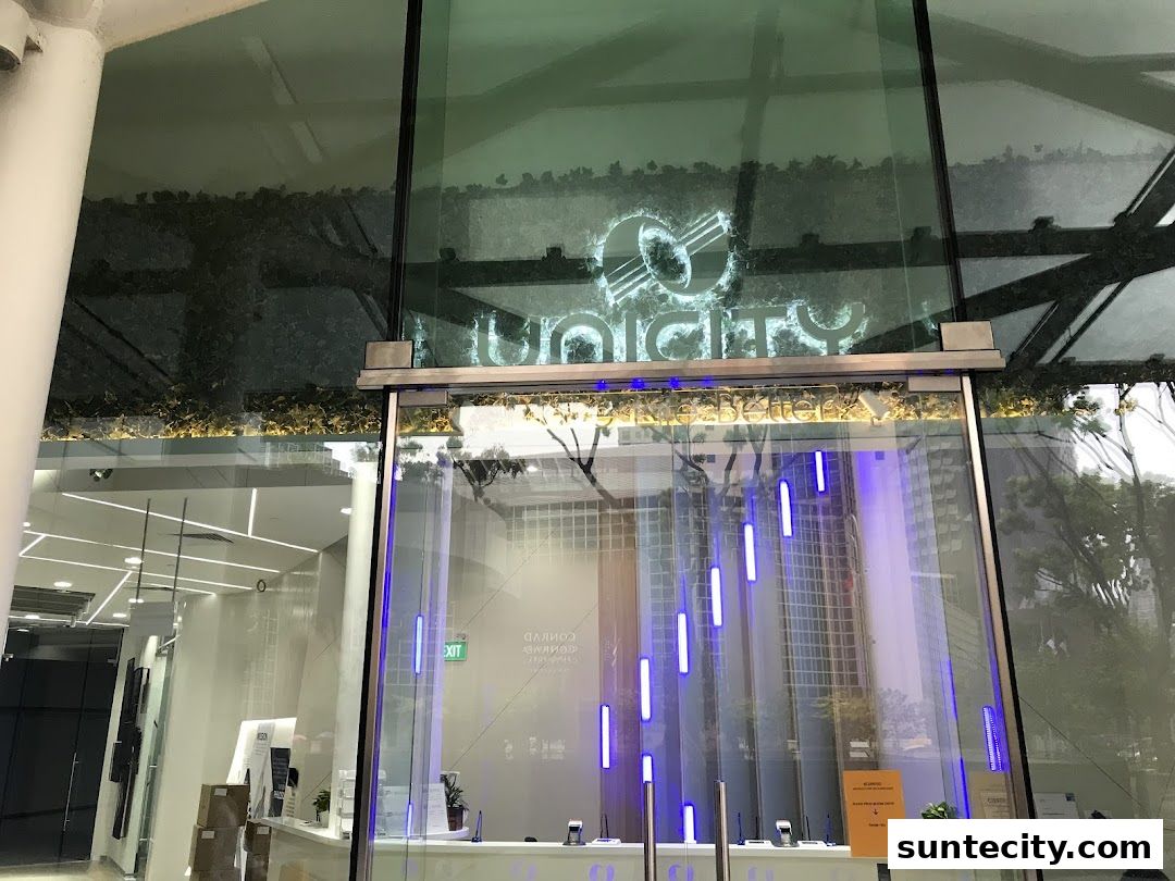 The modern glass entrance of the Unicity shop with illuminated signage and blue vertical lights.