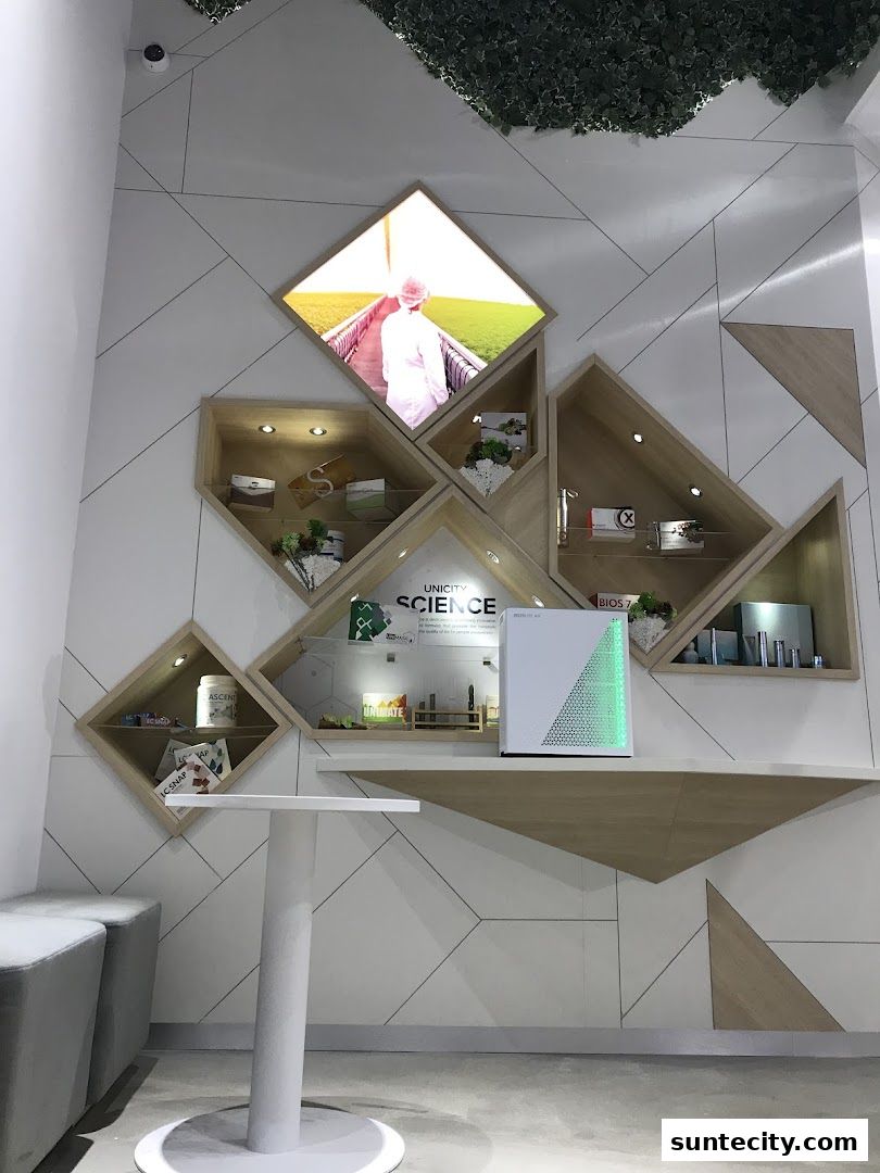 A modern retail display featuring geometric shelving with products and a large illuminated image.