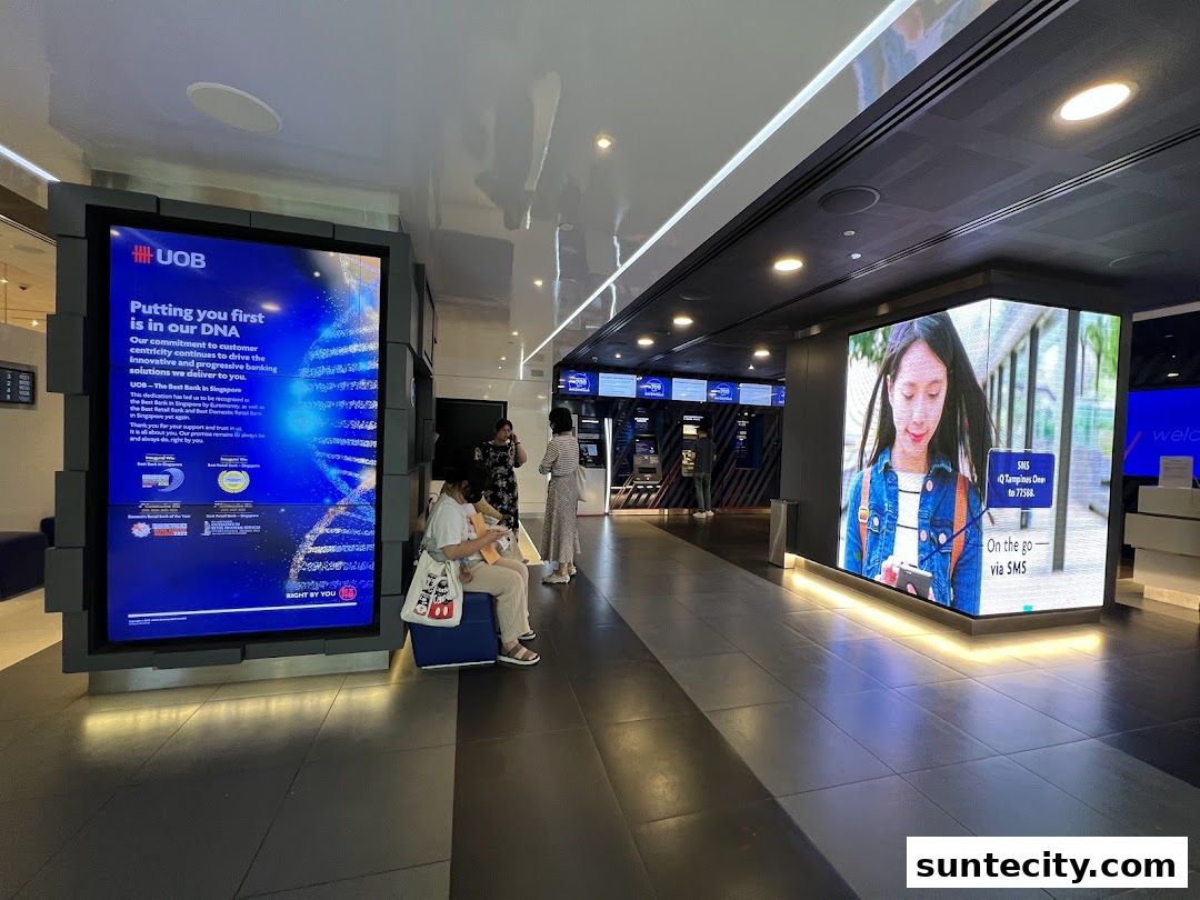 Interior of a UOB bank branch with digital displays and customers.