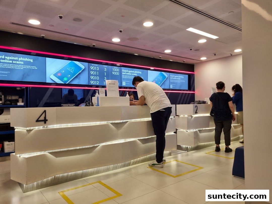 Customers queue at a UOB bank counter with digital displays showing scam warnings.