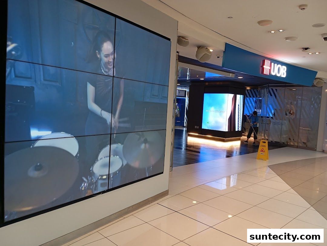 A UOB bank branch with a large screen displaying a drummer and a cleaner mopping the floor.