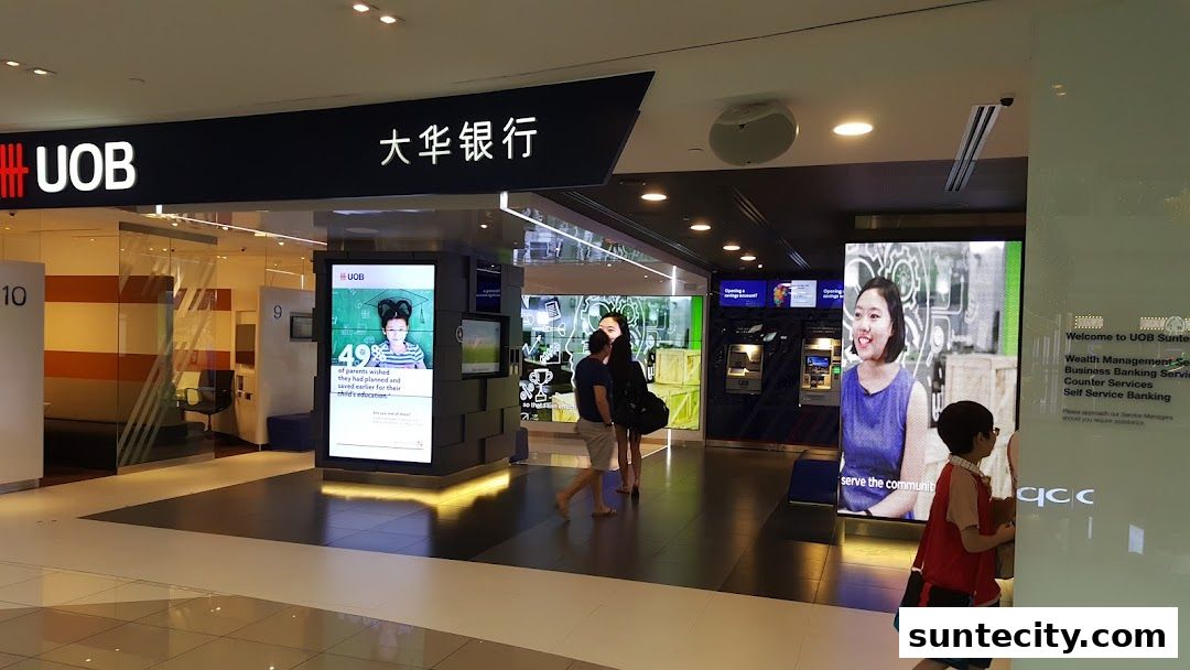 The entrance of a UOB bank branch with digital displays and people inside.