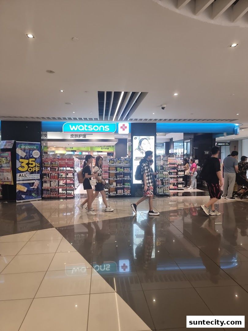 People walking past a Watsons pharmacy and GNC store in a mall.