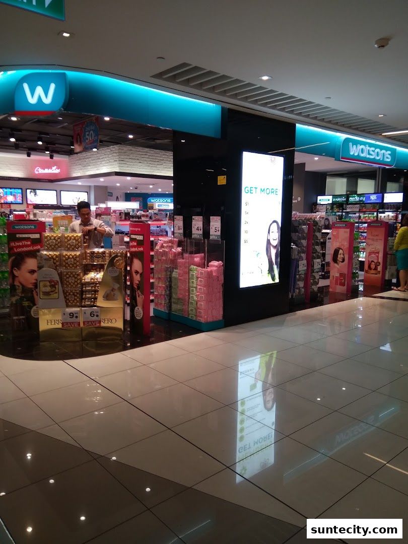 The exterior of a Watsons pharmacy and GNC store with various products displayed.