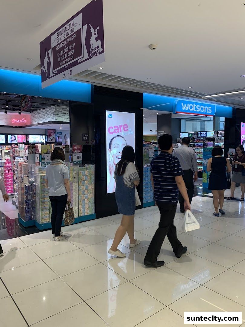 People walk past a Watsons store with a large 'care for me' advertisement.