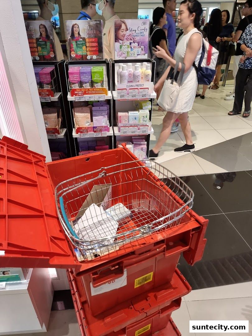 A Watsons store display featuring health and beauty products, with a shopping basket on red crates in the foreground.