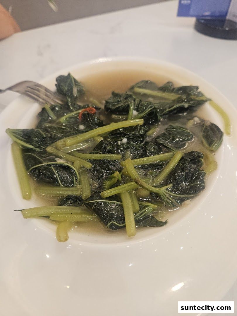 A close-up shot of a white bowl filled with stir-fried leafy green vegetables.