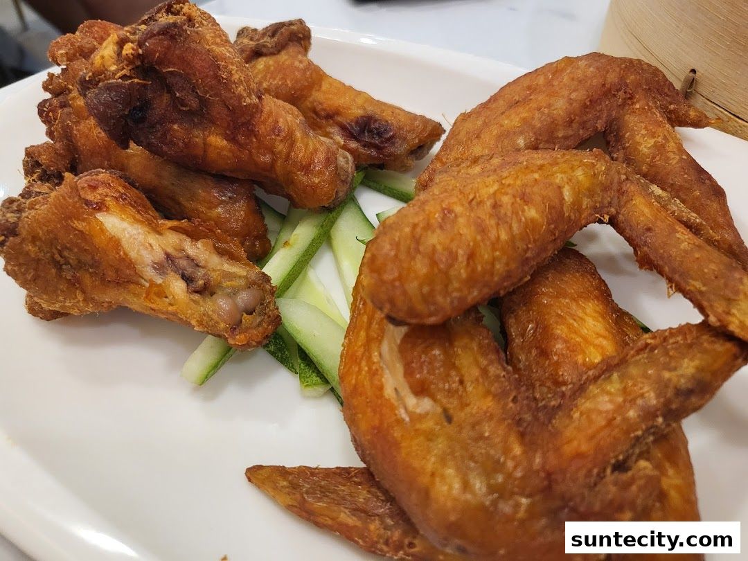 A plate of crispy fried chicken wings served with cucumber slices.