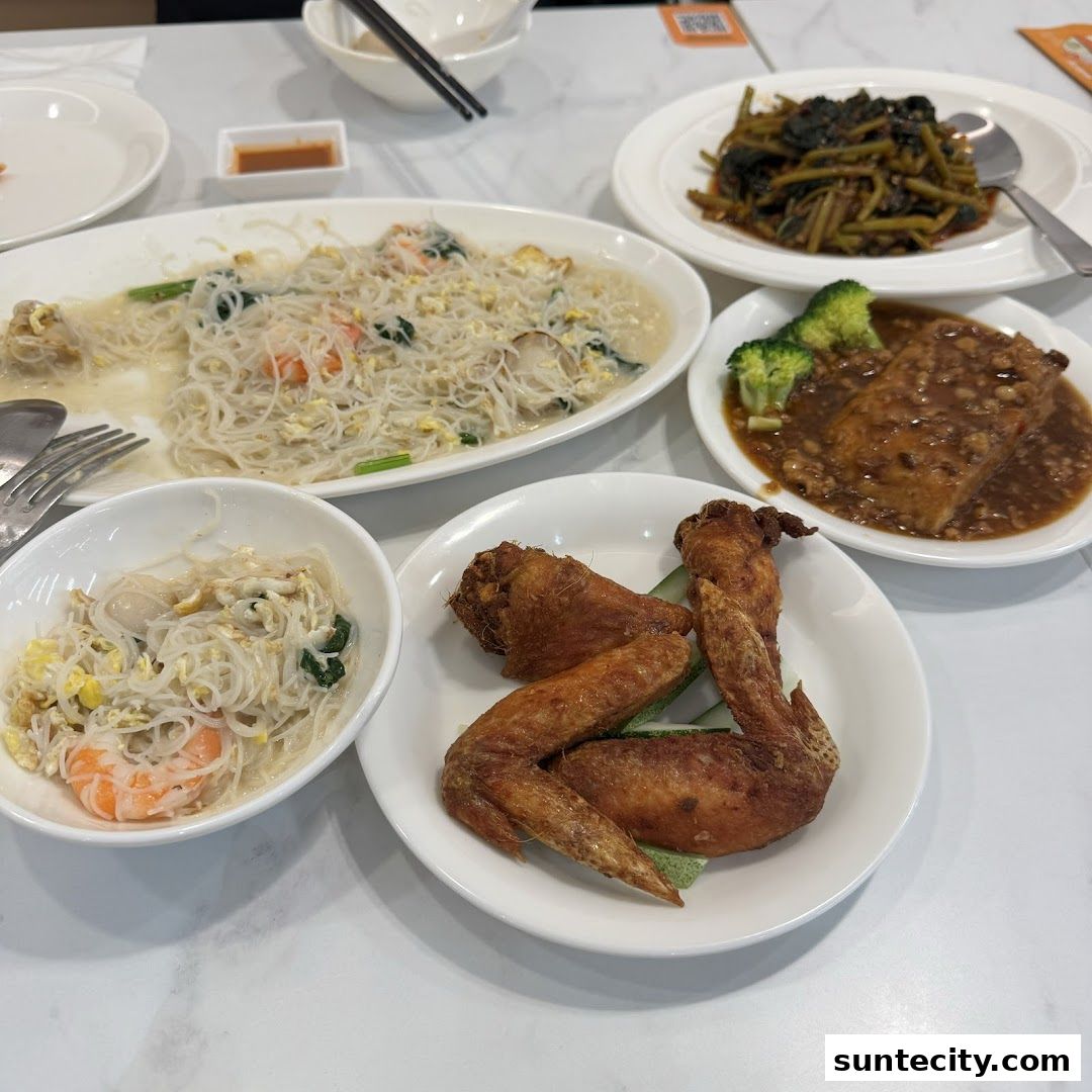 A table laden with various delicious dishes, including fried chicken wings and noodle dishes.