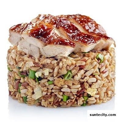 A close-up of a serving of fried rice topped with sliced grilled chicken.