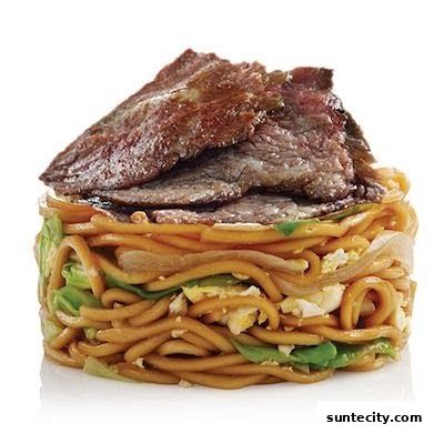 A close-up of a delicious noodle dish topped with thinly sliced beef.