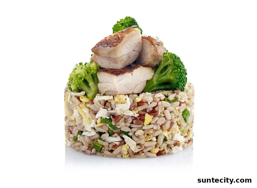 A serving of fried rice topped with grilled chicken pieces and broccoli florets.