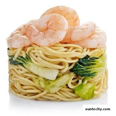 A close-up of a serving of noodles with bok choy and topped with shrimp.