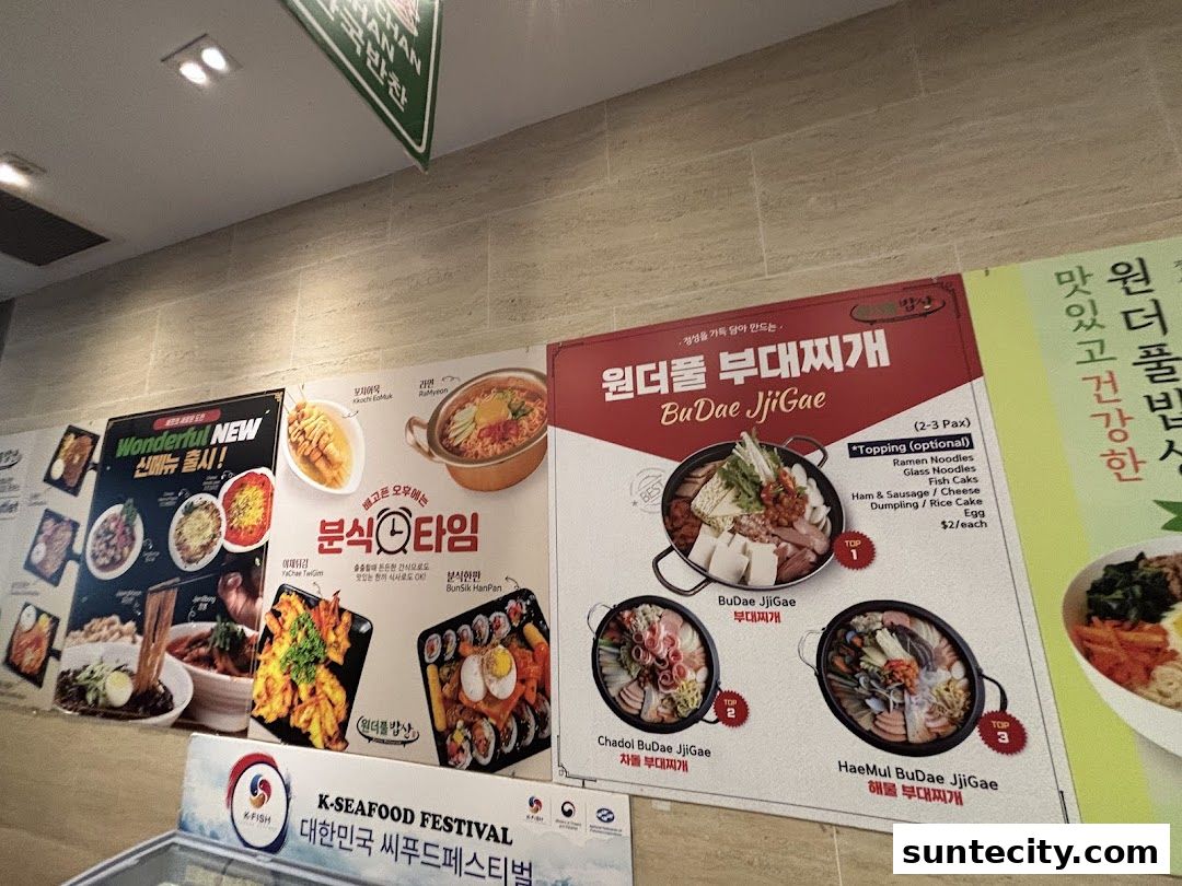A wall display showcasing various Korean dishes, including Budae Jjigae and other popular meals.
