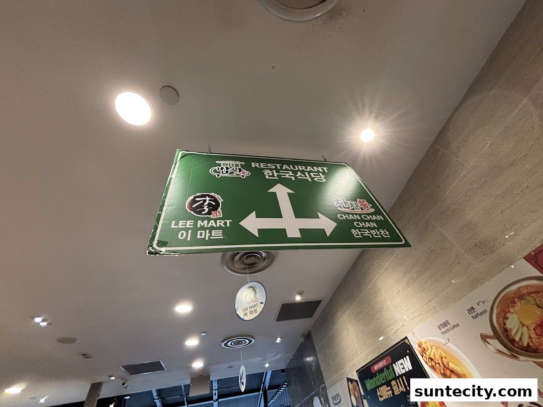 A directional sign for a Korean restaurant and market hangs from the ceiling.